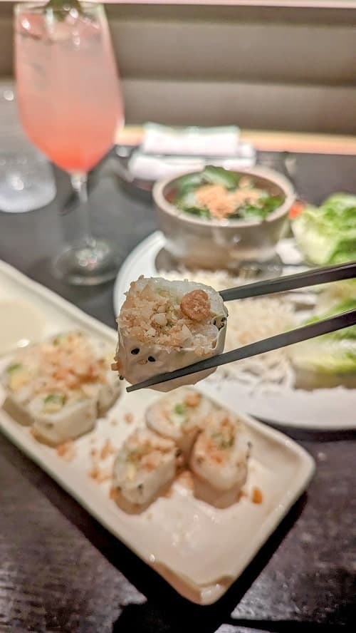 a vegan sushi roll held with chopsticks at planta in west palm beach