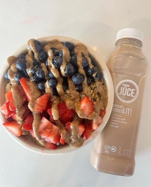acai bowl covered in almond butter and fresh fruit next to a vegan chocolate shake at raw juice in boca raton