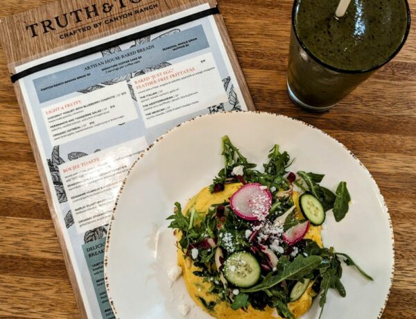 vegan egg omelet topped with frisee salad next to a green smoothie sitting on a truth and tonic menu in las vegas