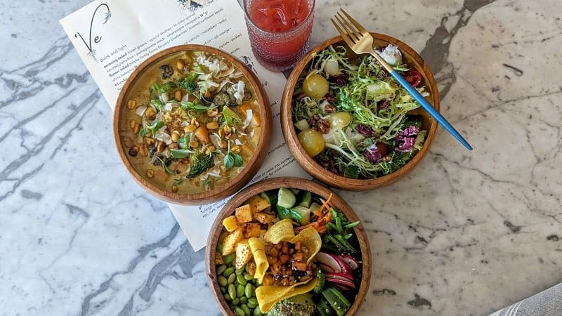 three colorful veggie bowls on a marble table at ve by subculture in west palm beach