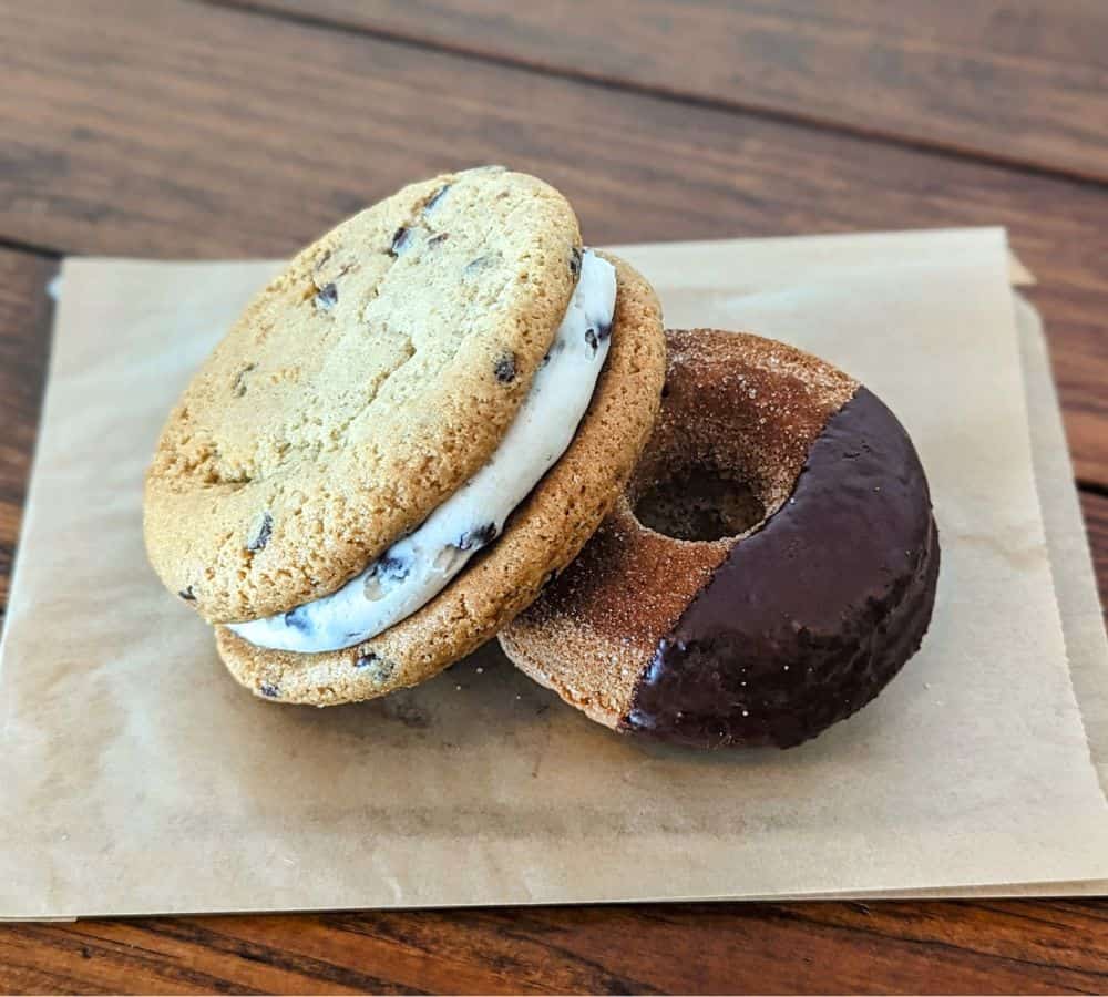 a vegan cookie sandwich next to a churro donut dipped in chocolate at parlour vegan bakery in boca raton