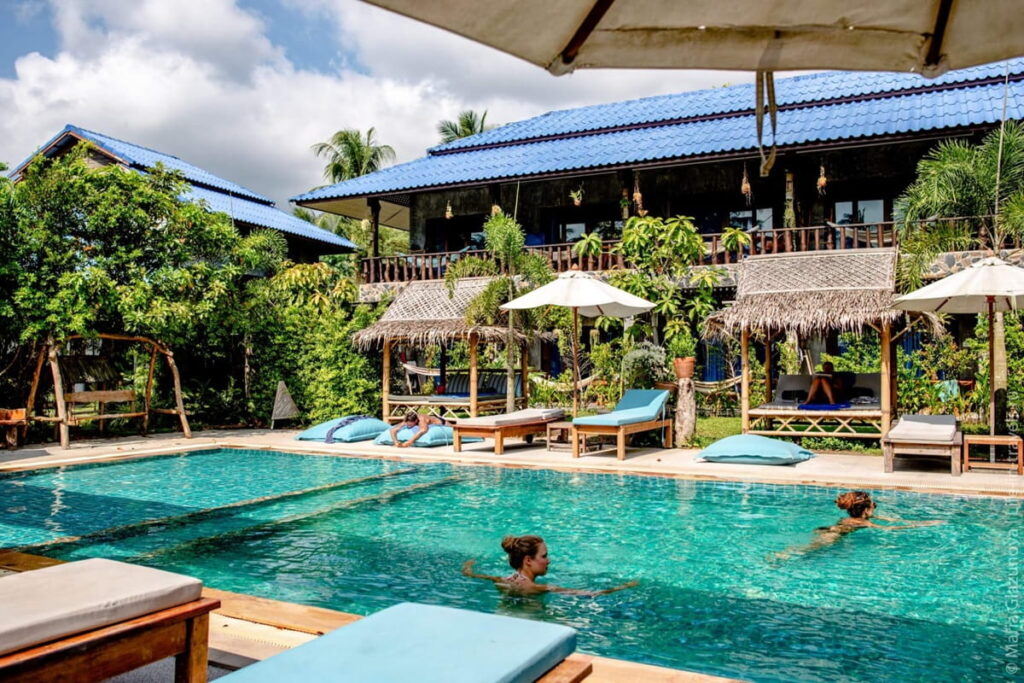 outdoor pool surrounded by lush greenery and beach chairs at the wonderland healing center in thailand