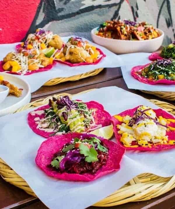 a spread of bright pink vegan tacos on a table at La Pitahaya Vegana in mexico city 