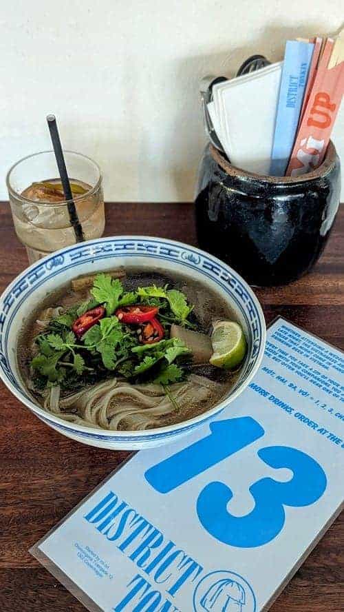 large bowl of vegan pho next to a ginger iced tea at district tonkin a vegan-friendly restaurant in copenhagen