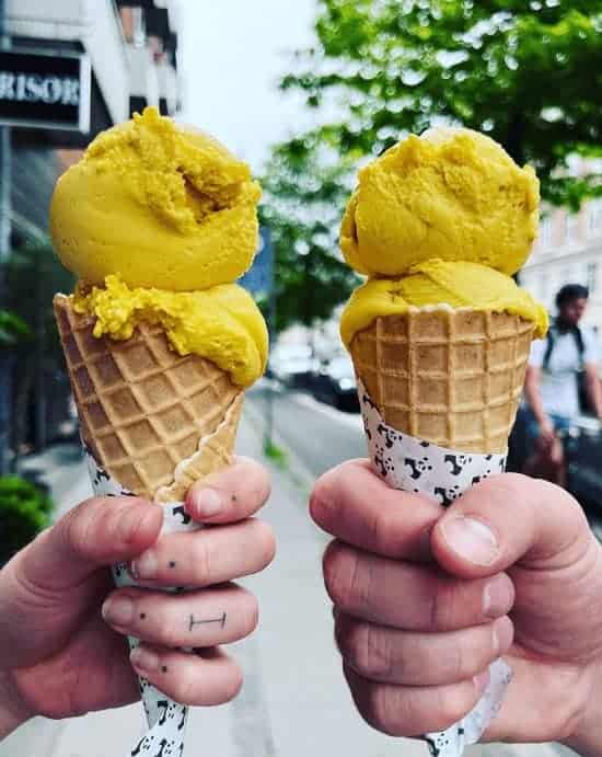 two vegan ice cream cones topped with two scoops of bright yellow mango ice cream from nice cream in copenhagen