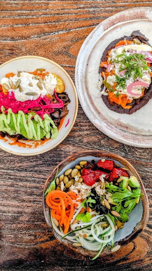 three colorful vegan veggie focused bowls on a wood table at su casa at the palmaia