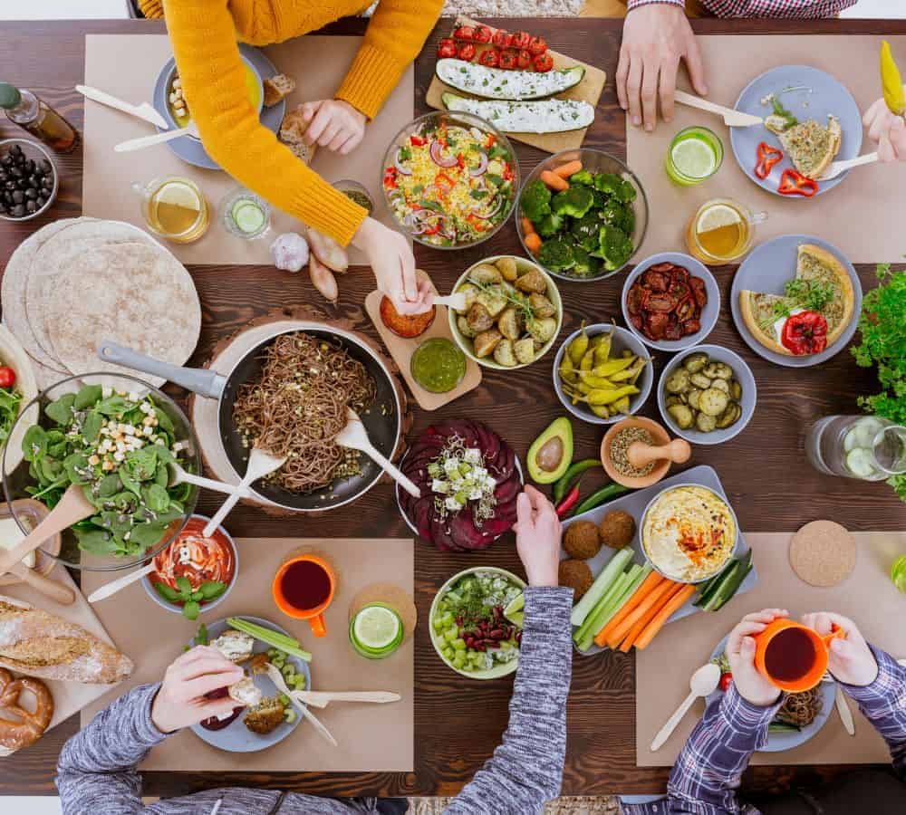 a group of people gathered around a table filled with colorful food and eating