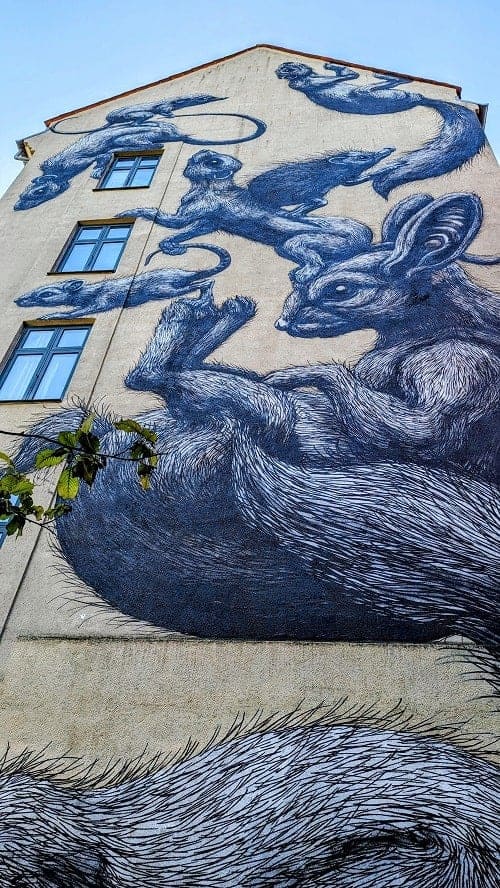 a mural of multiple squirrels falling down a side of a building in copenhagen