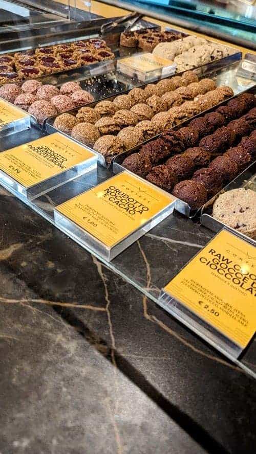 a display of vegan and gluten free cookies with bright yellow signs at Cortese Café 900 in florence