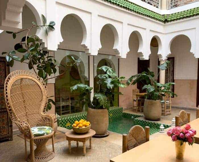 the court yard patio with a small pool and wicker furniture inside of the Monriad hotel in marrakech