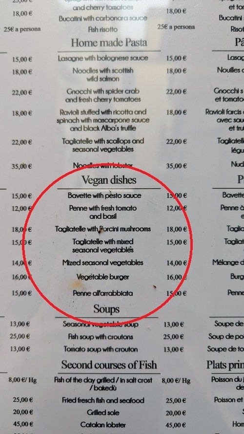 a white menu with a circle in the middle surrounding a small listing of vegan options at the restaurant Osteria Barababao  in venice italy