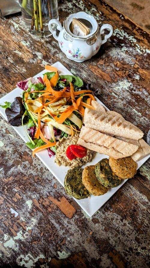 a white plate with a colorful salad and falafel at Sullaluna Libreria & Bistrot