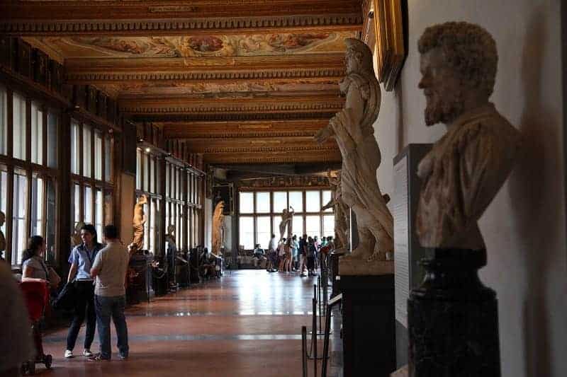 the dimly lit The Uffizi Gallery lined with sculptures down a hallway