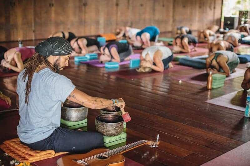 a man hosting a yoga class during a retreat at the vegan-friendly yogabarn in bali