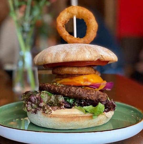 a giant vegan burger topped with a large golden onion ring at apple and eve soul food in hamburg