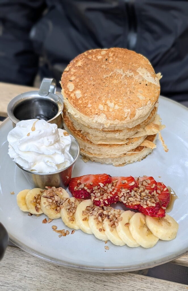 a stack of three small like golden pancakes with syrup and strawberries at cafe vegetal in cdmx