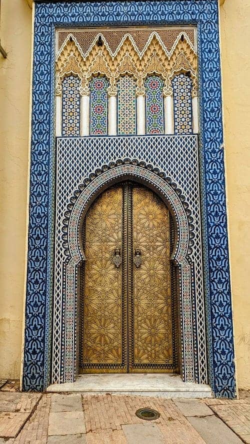 ornate bronze door surrounded by blue tile mosaics in morocco