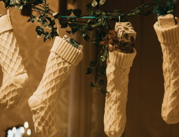 four white christmas stocking hanging from green garland in a dimly lit room
