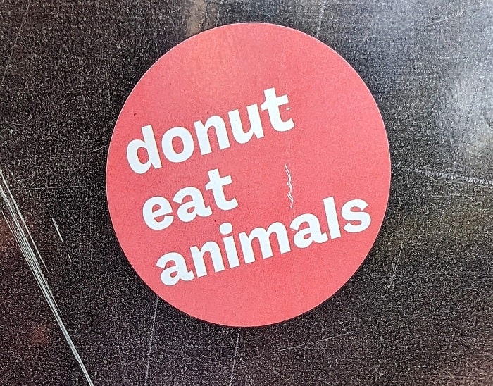 a pink sticker on a dark background that says donut eat animals