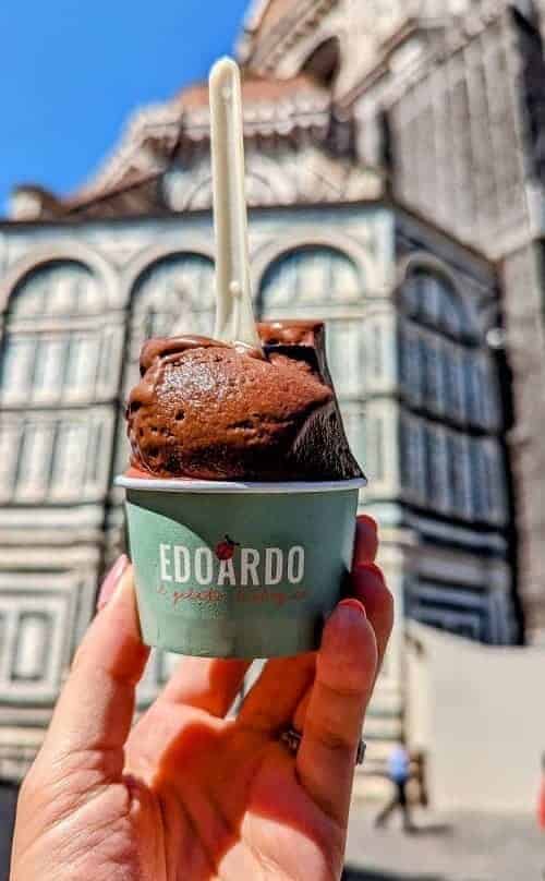a scoop of vegan dark chocolate hazelnut gelato in a green cup in front of the duomo in florence