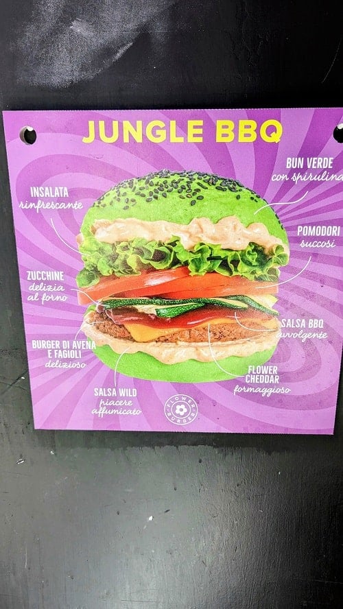 a sign for a burger with a bright green bun at flower burger in florence 