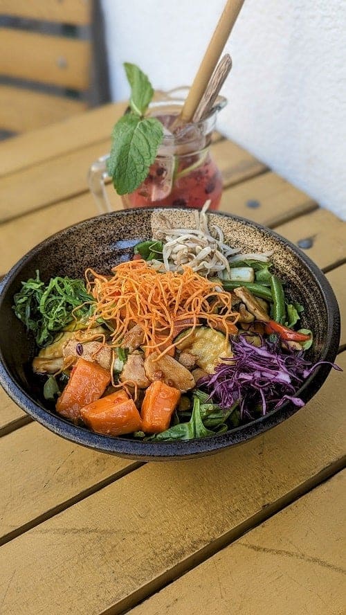 colorful vegan Vietnamese veggie bowl next to a fruity iced tea at greentable in hamburg