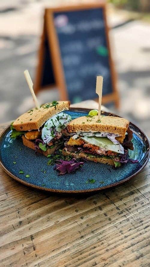 a vegan tempeh sandwich on a blue plate at happenpappen in hamburg