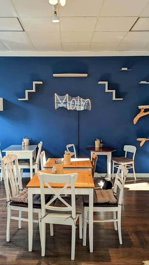 the dining room area with a dark blue wall with a sign that says moin at the cat cafe katers kook in hamburg