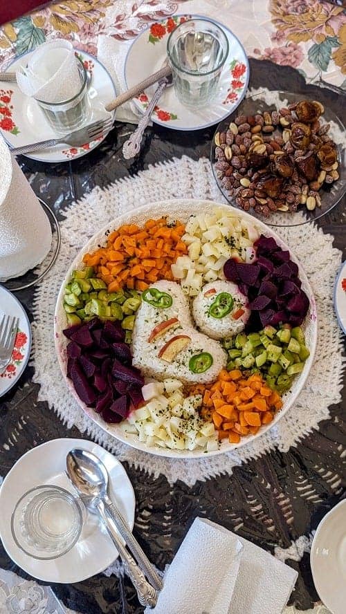 a large round platter filled with cooked vegetables and rice next to a bowl of nuts in morocco