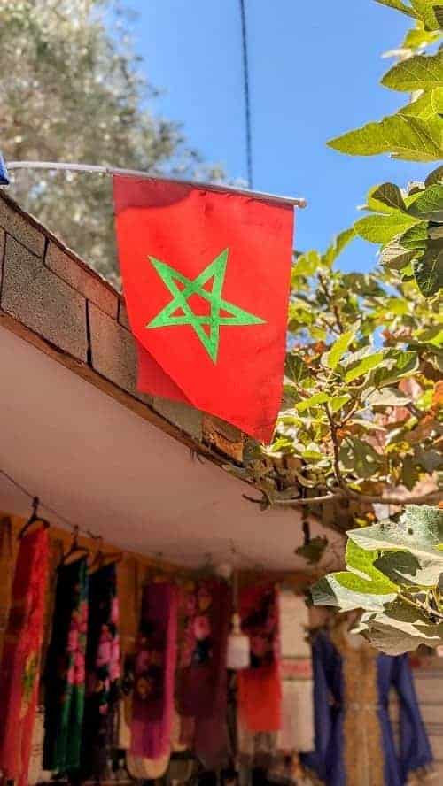 red moroccan flag with a green star in the middle hanging from a shop in morocco