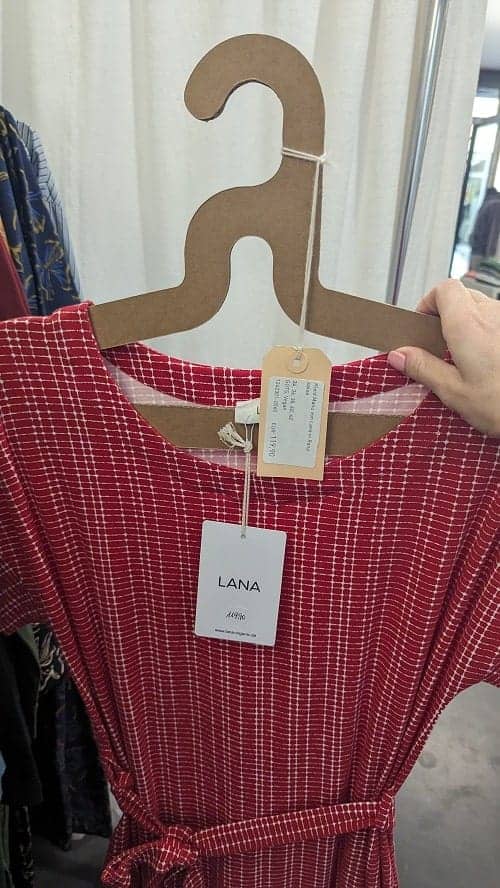 a red dress with a faint white pattern hanging on an eco friendly cardboard hanger in hamburg