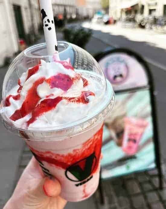 a vegan strawberry milkshake topped with whipped cream and red strawberry drizzle in copenhagen