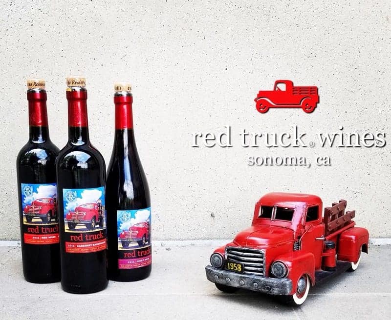 three bottles of vegan wine from red truck vineyards sitting next to a red truck on a white background
