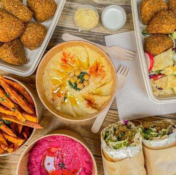 spread of vegan falafel, wrap sandwich, bright pink hummus and french fries at santo falafel in florence