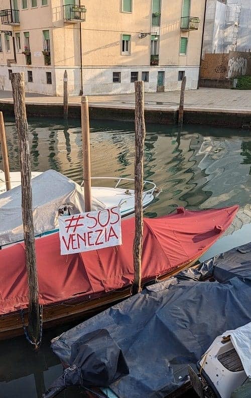 a white sign with red lettering on a boat that says #sosvenezia