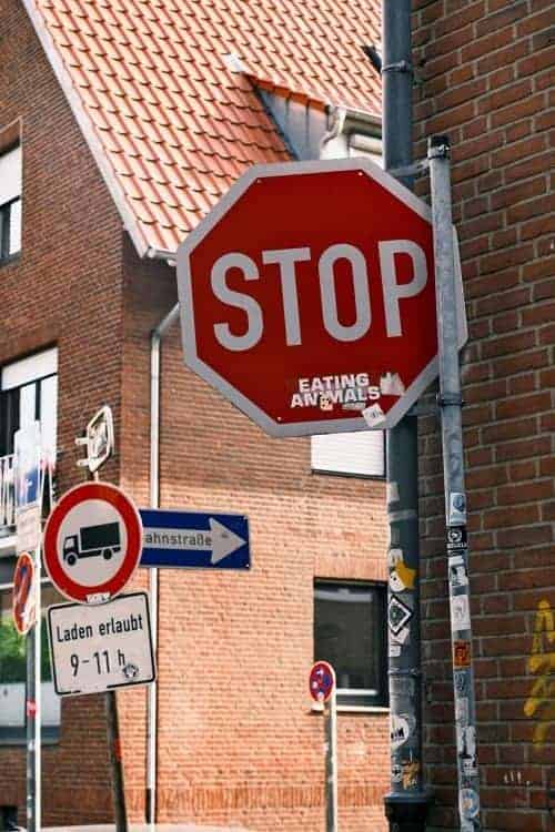 a red stop sign on the street with a sticker below stop that says eating animals