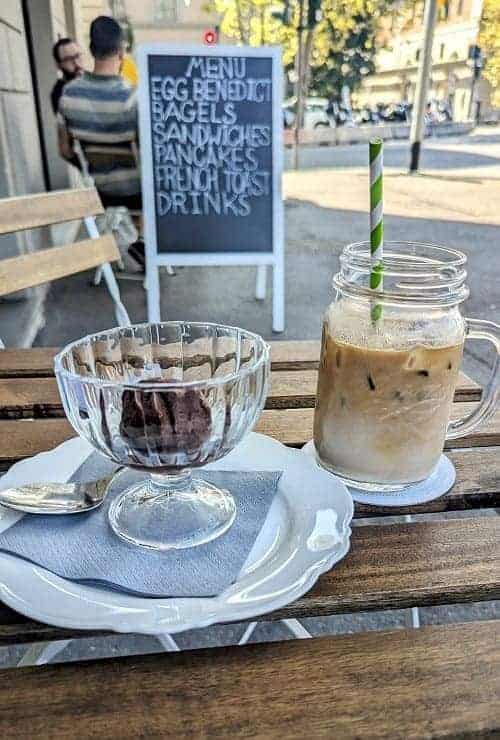 a scoop of vegan dark chocolate gelato in a large glass bowl next to an iced oatmilk latte at valu bakery in florence