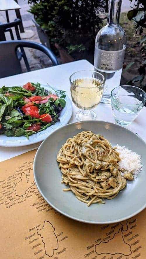 a bowl of creamy vegan pasta next to a green salad and a glass of wine at veg nirvana in florence 