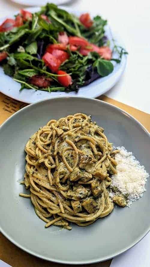 a bowl of creamy vegan pasta next to a green salad at veg nirvana in florence 