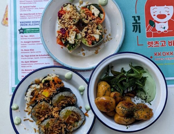 three different vegan korean dishes sitting on top of a teal and red menu at a restaurant in hamburg