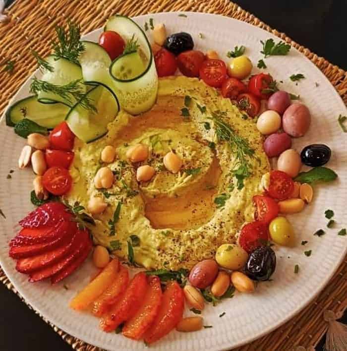 a white round platter with fresh hummus and vegetables at the vegetarian restaurant veggie pause in fes