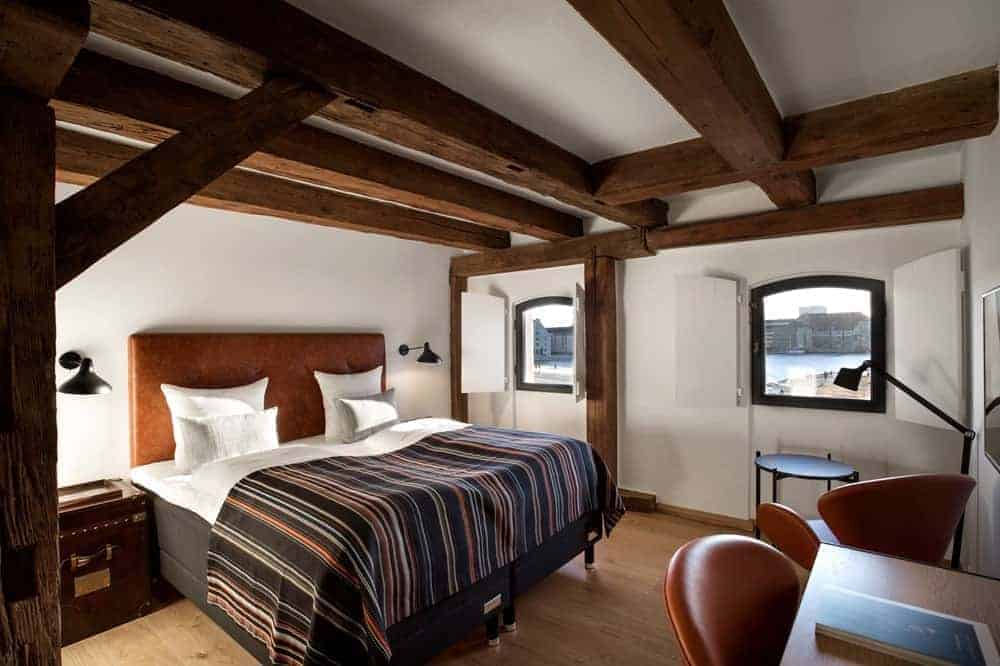 inside of a rustic guestroom with wood beams and natural accents at the eco friendly nyhavn hotel in copenhagen