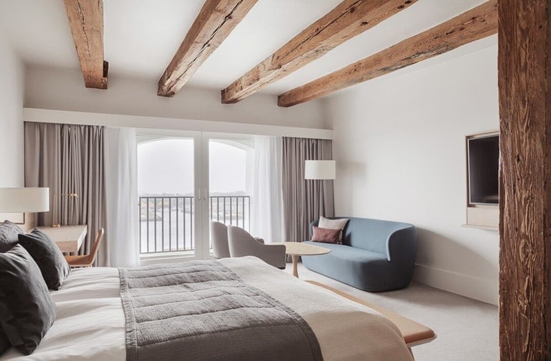 guest suite at the admiral hotel in copenhagen decorated with neutral colors and natural fabrics and large exposed wood beams in the ceiling 