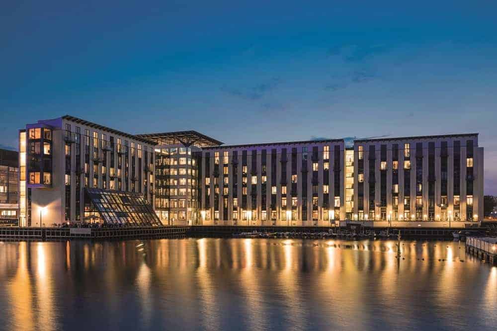 the facade of the Copenhagen island hotel at night all lit with warm lights