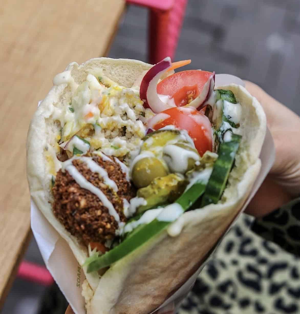vegan falafel wrap topped with a cream sauce and loaded with veggies from maoz amsterdam