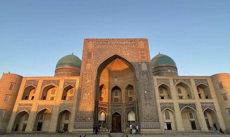 Mir-i-Arab Madrasa in Bukhara bosque with brown facade and blue tilework
