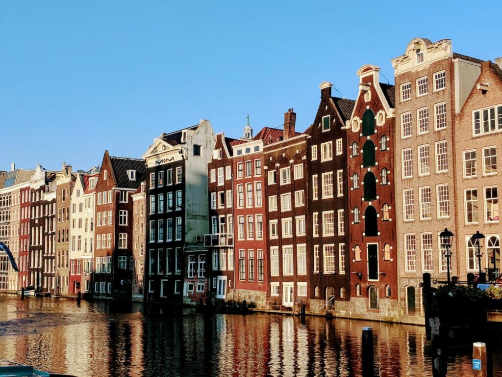 skinny canal houses lined up along a still canal in Amsterdam just before the sunsets