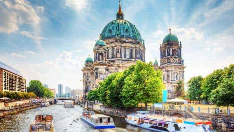 boats passing the large green bronze topped berlin cathedral on a sunny day in berlin