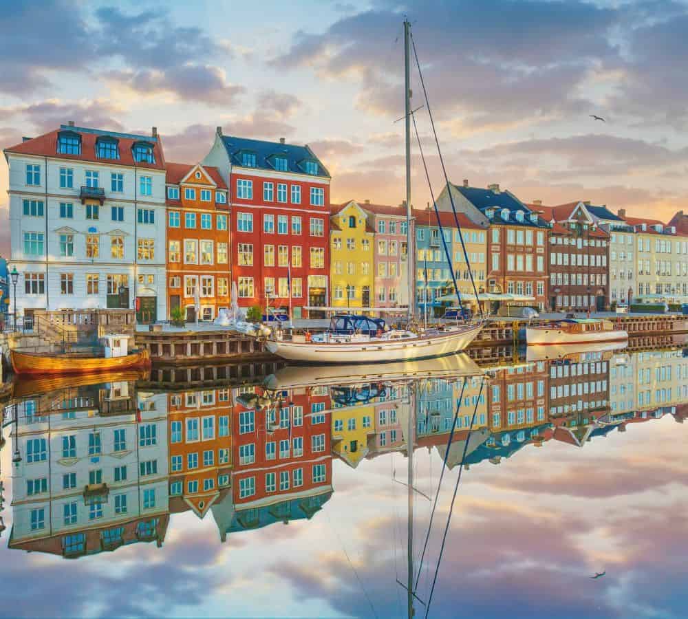 copenhagen's historic harbor late in the day with the reflection of the colorful building lining the harbor in the water
