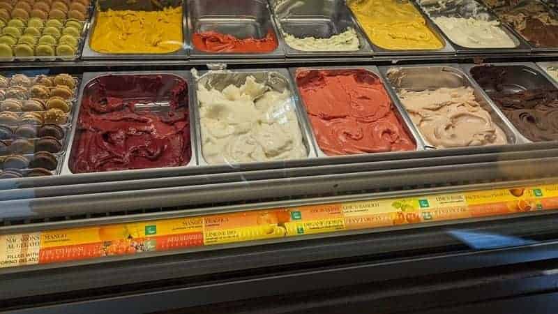 a display case filled with brightly colored vegan gelato flavors at ice cream festival in florence